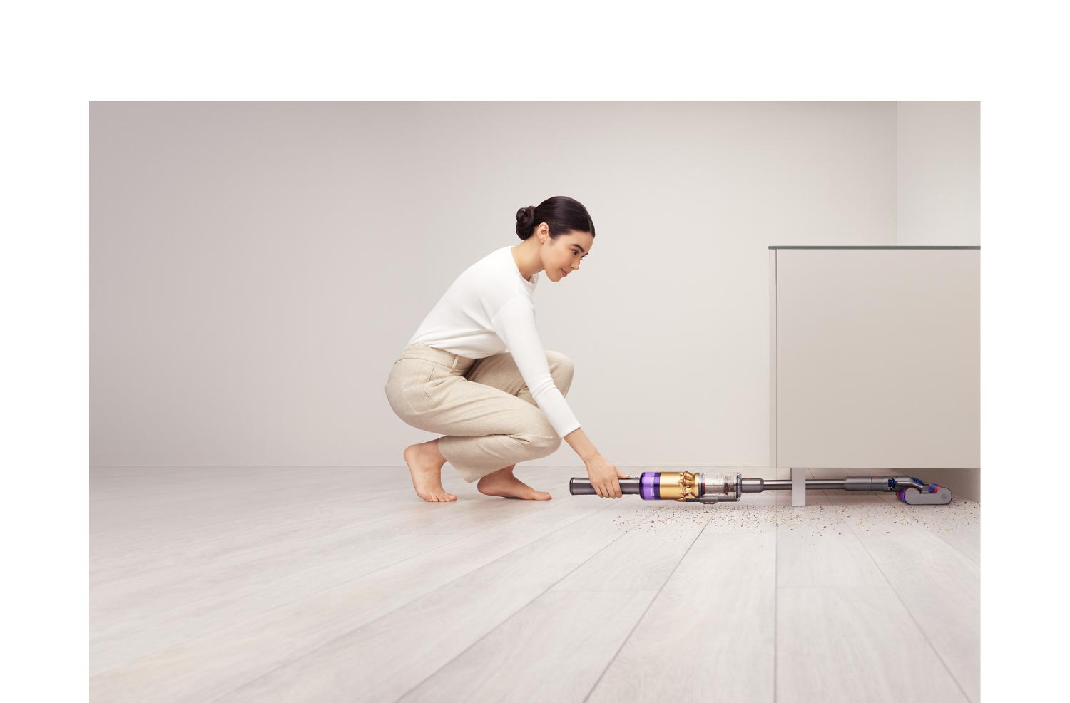 戸棚の下をDyson Omni-glideで掃除する女性。